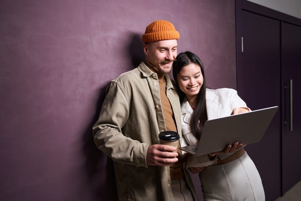 Joyous interracial couple using portable computer indoors, online presence, public relations, social media