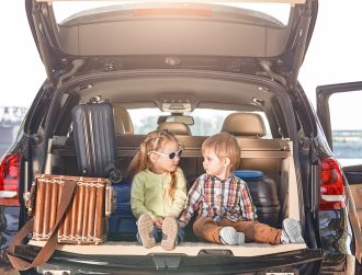 No road is long with good company. Little cute kids in the trunk of a car with suitcases looking at