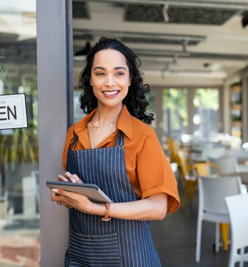 Small business entrepreneur at cafe entrance using digital tablet