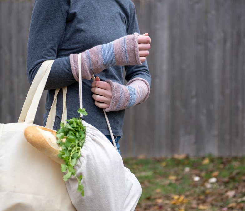 Woman carrying reusable canvas bags filled with groceries outdoors