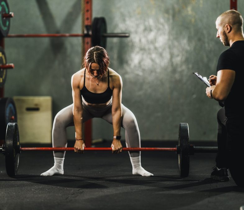 Woman Exercising With Personal Trainer At The Gym