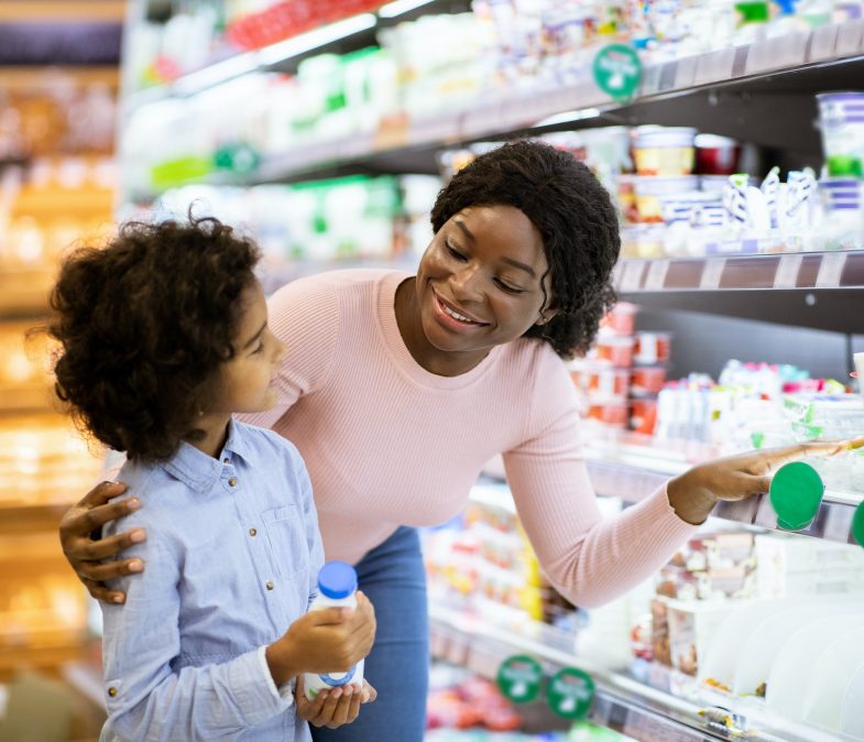 Young black mother with her daughter shopping for dairy products at supermarket